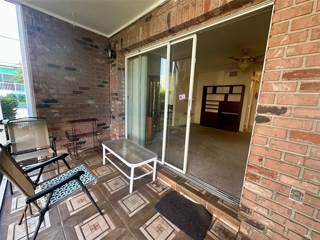 A covered brick patio features tiled flooring, outdoor furniture, and a sliding glass door entrance — 4115 34TH WAY S UNIT 194, ST PETERSBURG, FL