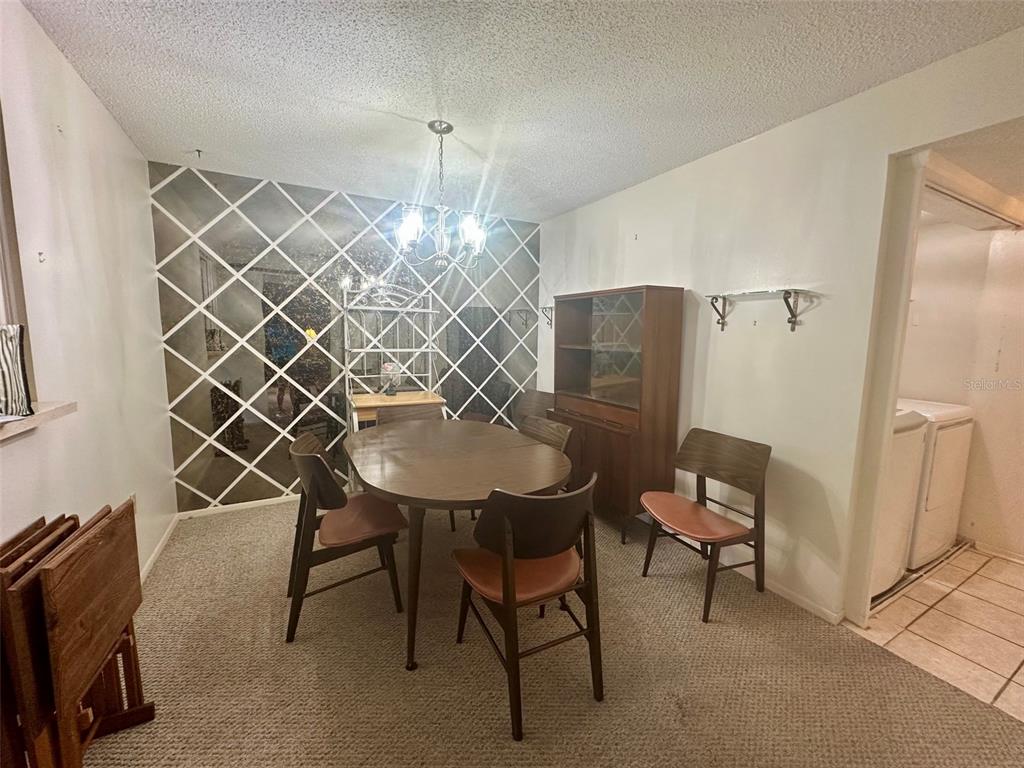 A dining room features a mirrored wall, a round wooden table, and mid-century modern chairs — 4115 34TH WAY S UNIT 194, ST PETERSBURG, FL