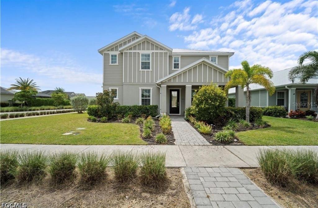 A two-story house with light gray siding features a front porch and a paved walkway — 42226 LAKE TIMBER DRIVE, PUNTA GORDA, FL