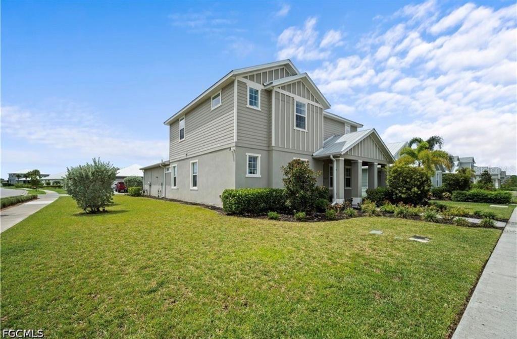 A two-story house with light-colored siding and a covered front porch sits on a lawn — 42226 LAKE TIMBER DRIVE, PUNTA GORDA, FL