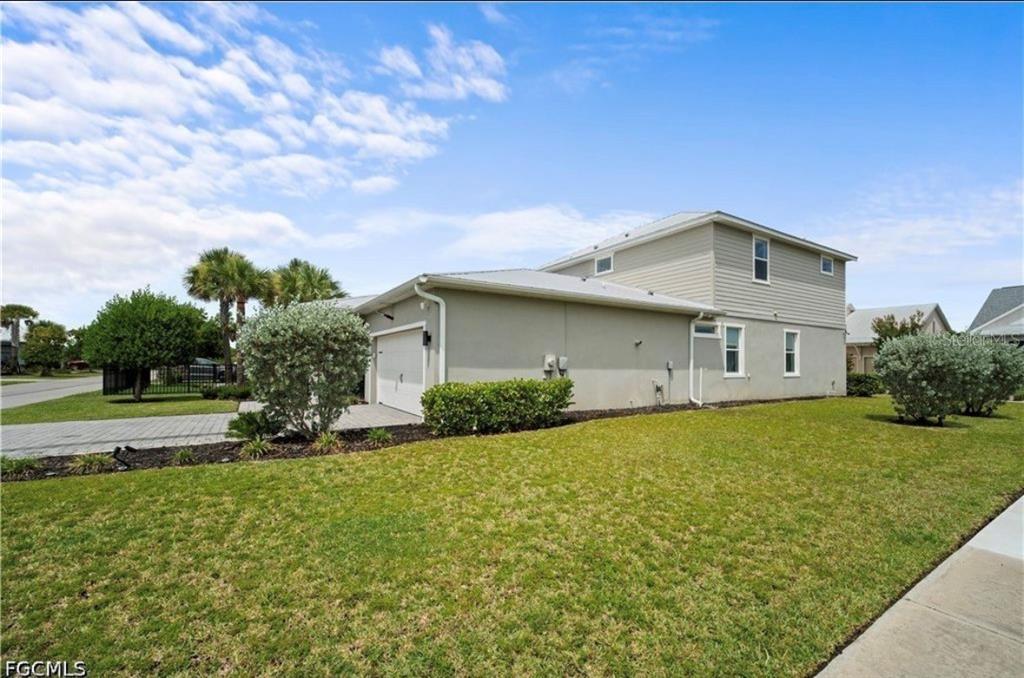 A two-story house with a light-colored exterior, a garage, and a manicured lawn — 42226 LAKE TIMBER DRIVE, PUNTA GORDA, FL
