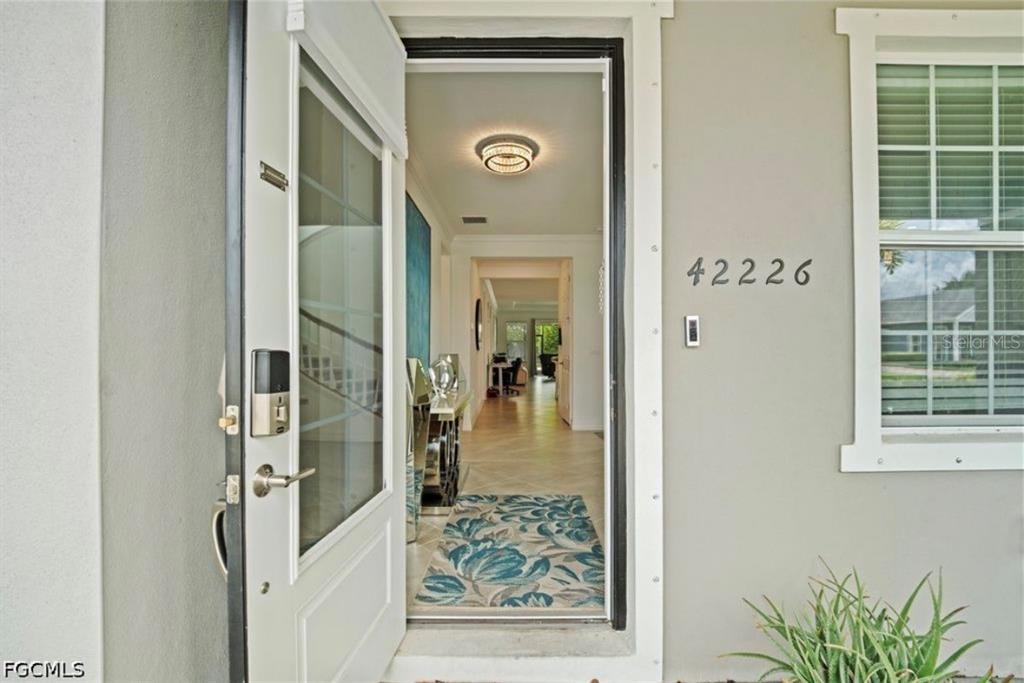 An open front door reveals a tiled entryway with a patterned rug and interior hallway — 42226 LAKE TIMBER DRIVE, PUNTA GORDA, FL