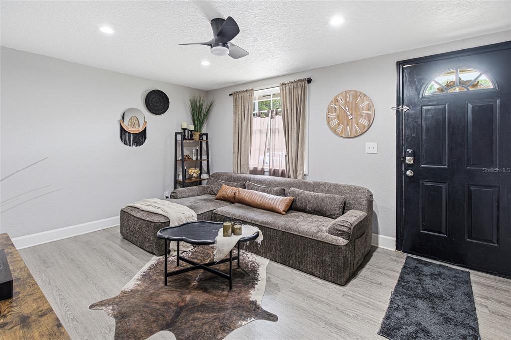 A living room features a grey sectional sofa, a cowhide rug, and a black door — 7709 PASCHAL STREET, JACKSONVILLE, FL