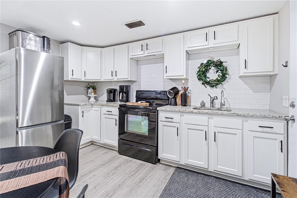 A kitchen features white cabinets, granite countertops, a black stove, and a stainless steel refrigerator — 7709 PASCHAL STREET, JACKSONVILLE, FL