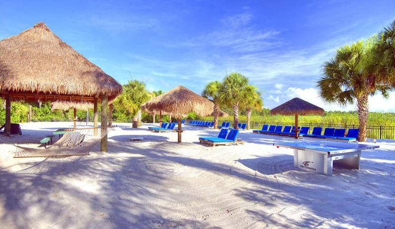 A sandy beach area features several thatched-roof palapas, lounge chairs, a hammock, and a ping-pong table — 603 NEW PROVIDENCE UNIT 603, DAVENPORT, FL