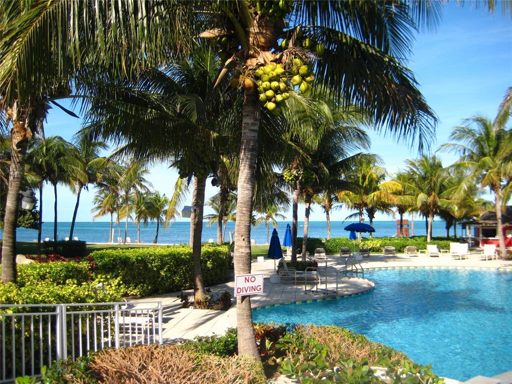 A swimming pool sits next to palm trees and a beach with a blue ocean view — 603 NEW PROVIDENCE UNIT 603, DAVENPORT, FL