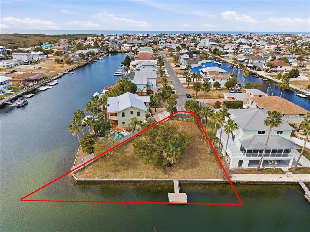 An aerial view shows a vacant triangular waterfront lot with a dock and palm trees — 4064 CASA COURT, HERNANDO BEACH, FL