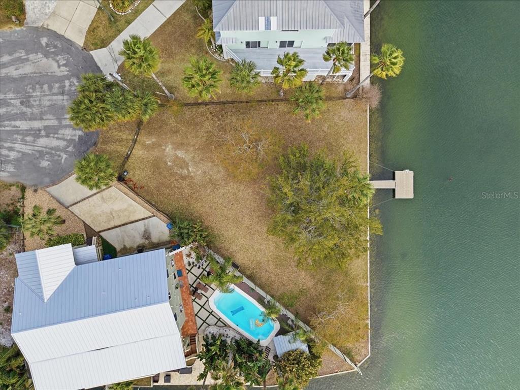 An aerial view shows a waterfront property with a house, pool, and private dock — 4064 CASA COURT, HERNANDO BEACH, FL