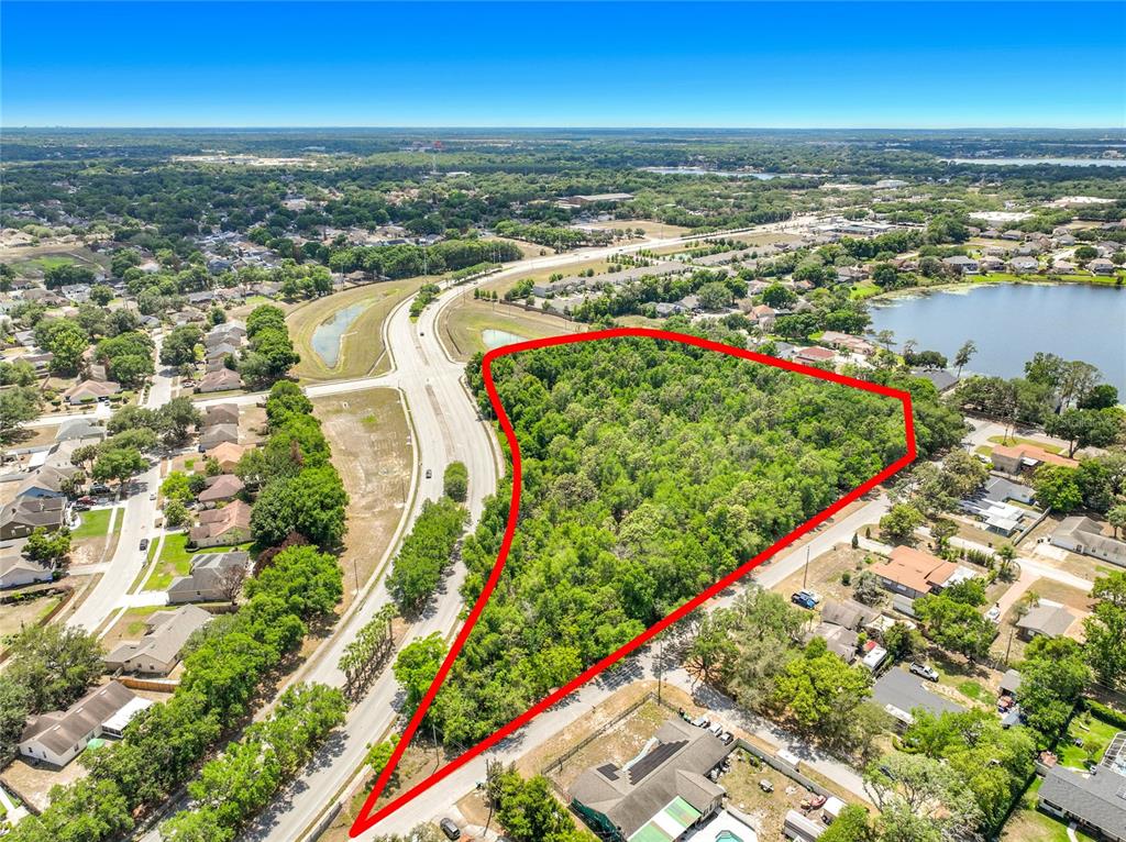 An aerial view shows a triangular, tree-covered vacant lot outlined in red next to roads — 1900 E SILVER STAR ROAD, OCOEE, FL