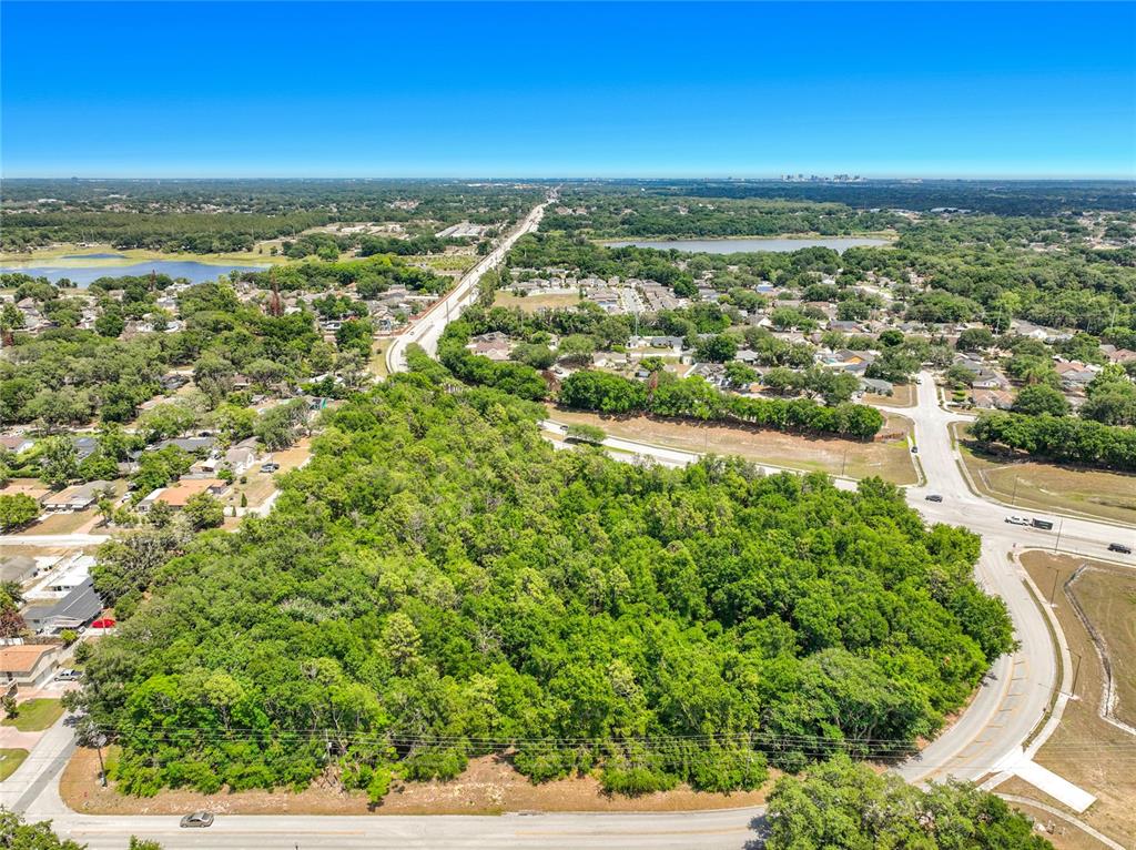 An aerial view shows a large, wooded vacant lot bordered by residential streets and houses — 1900 E SILVER STAR ROAD, OCOEE, FL