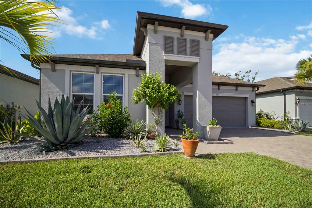 An aerial view shows the shingled roof of a house with solar panels and landscaping — 14814 SORA WAY, BRADENTON, FL