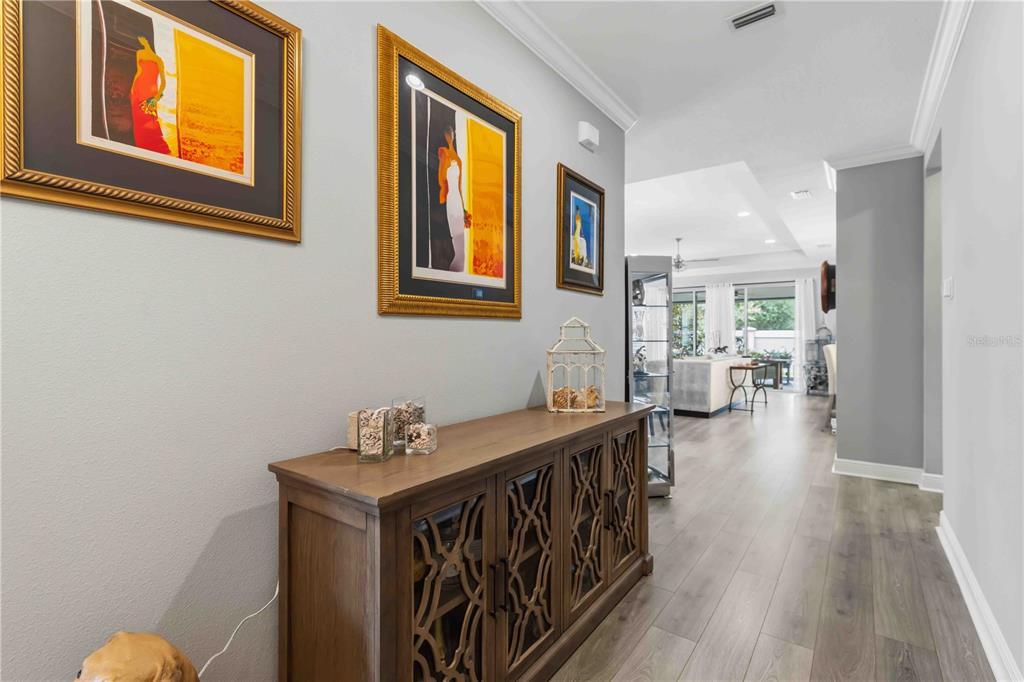An open-concept dining and living area features light wood floors, tray ceilings, and sliding doors — 14814 SORA WAY, BRADENTON, FL