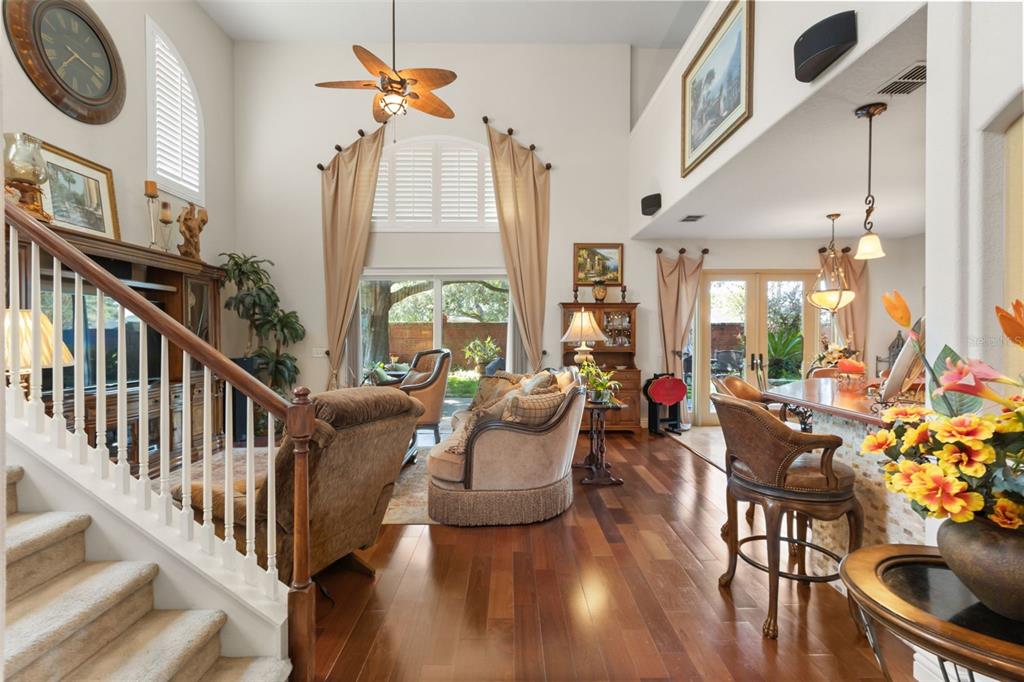 A living room with hardwood floors, a staircase, and a view of the backyard — 393 LAKE AMBERLEIGH DRIVE, WINTER GARDEN, FL