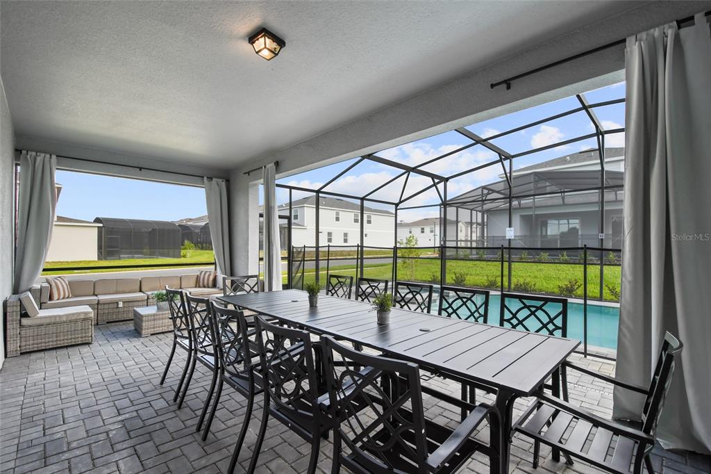 A covered patio features a dining table, outdoor seating, and a screened-in pool area — 16364 SAINT KITTS CIRCLE, CLERMONT, FL