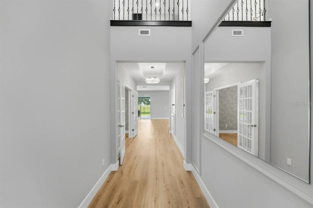 A hallway with light wood floors, a large wall mirror, and a view toward a backyard — 5024 PALMETTO PARK DRIVE, WINTER GARDEN, FL