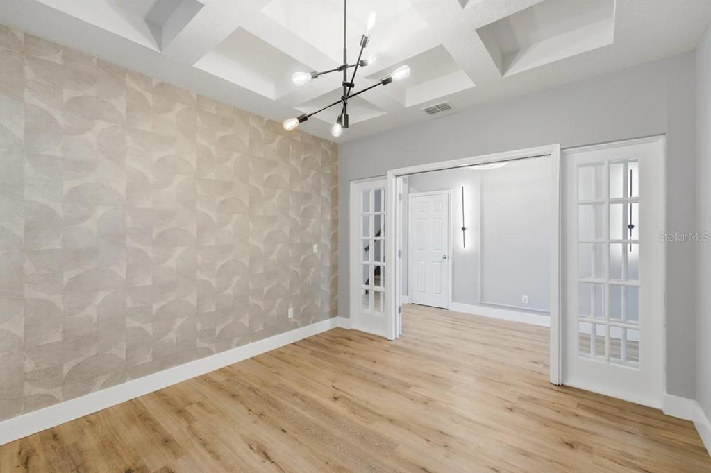 A room with light wood flooring, a patterned accent wall, and a modern geometric chandelier — 5024 PALMETTO PARK DRIVE, WINTER GARDEN, FL