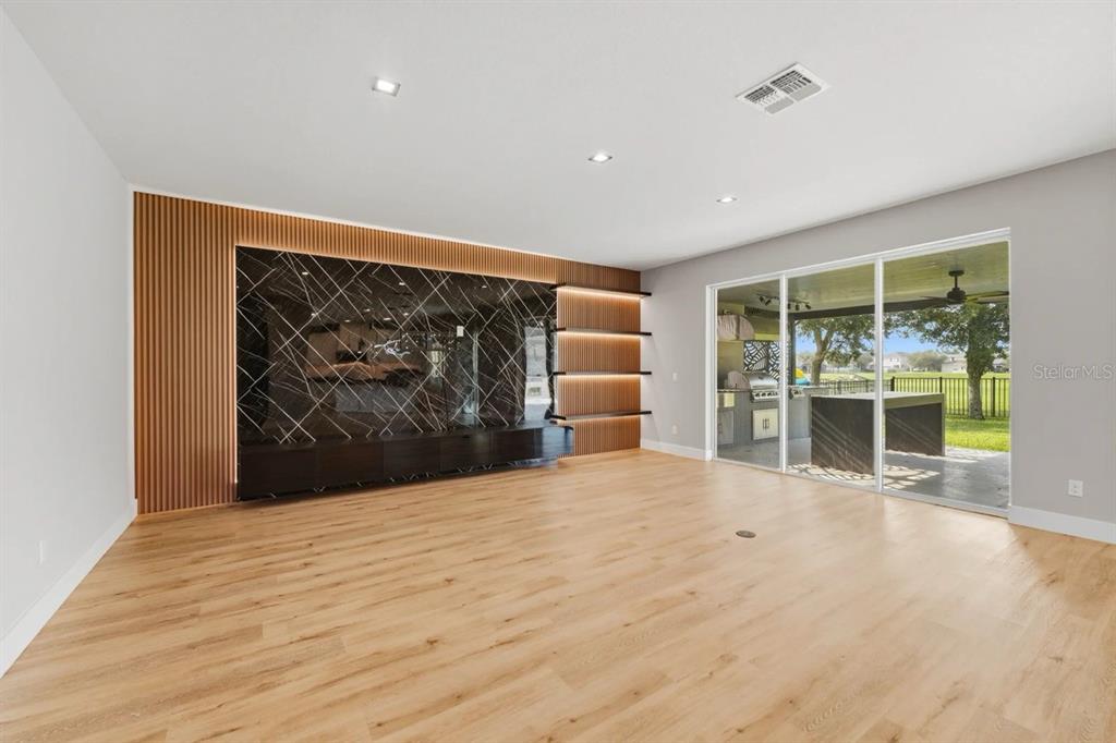 A living room features light wood flooring, a black marble accent wall, and sliding glass doors — 5024 PALMETTO PARK DRIVE, WINTER GARDEN, FL
