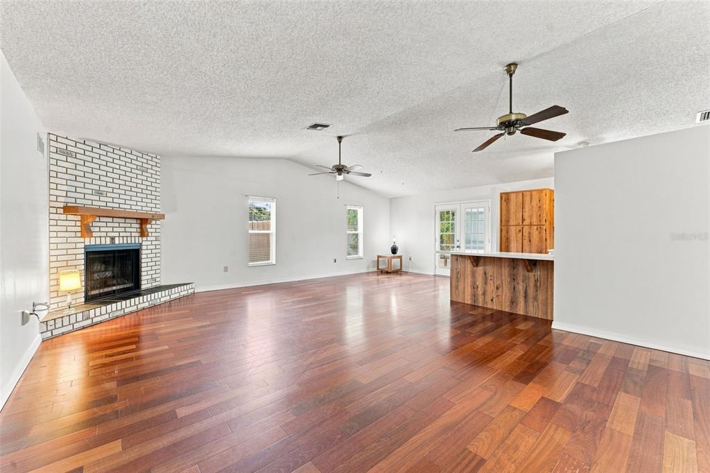 A living room features wood flooring, a white brick corner fireplace, and two ceiling fans — 2202 CITRUS HILL LANE, PALM HARBOR, FL