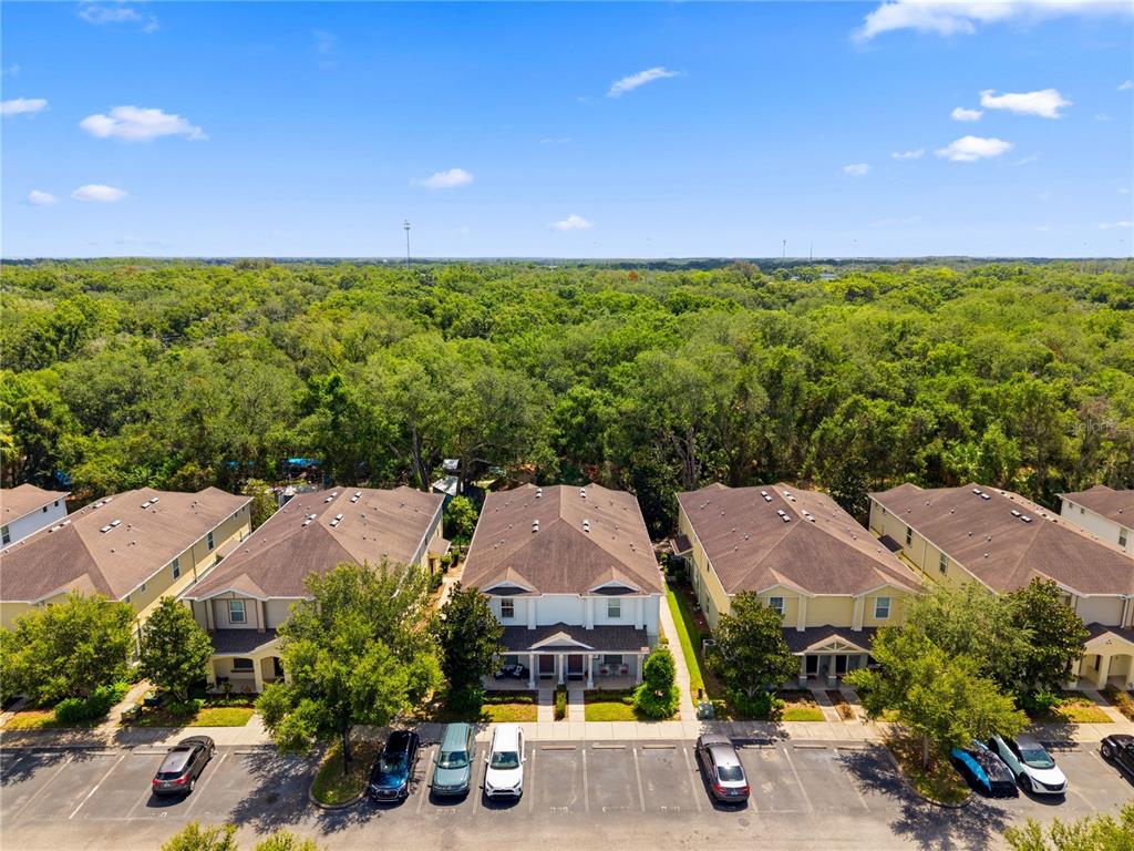 An aerial view shows a row of townhomes with parking spaces in front and trees behind — 4824 CHATTERTON WAY, RIVERVIEW, FL