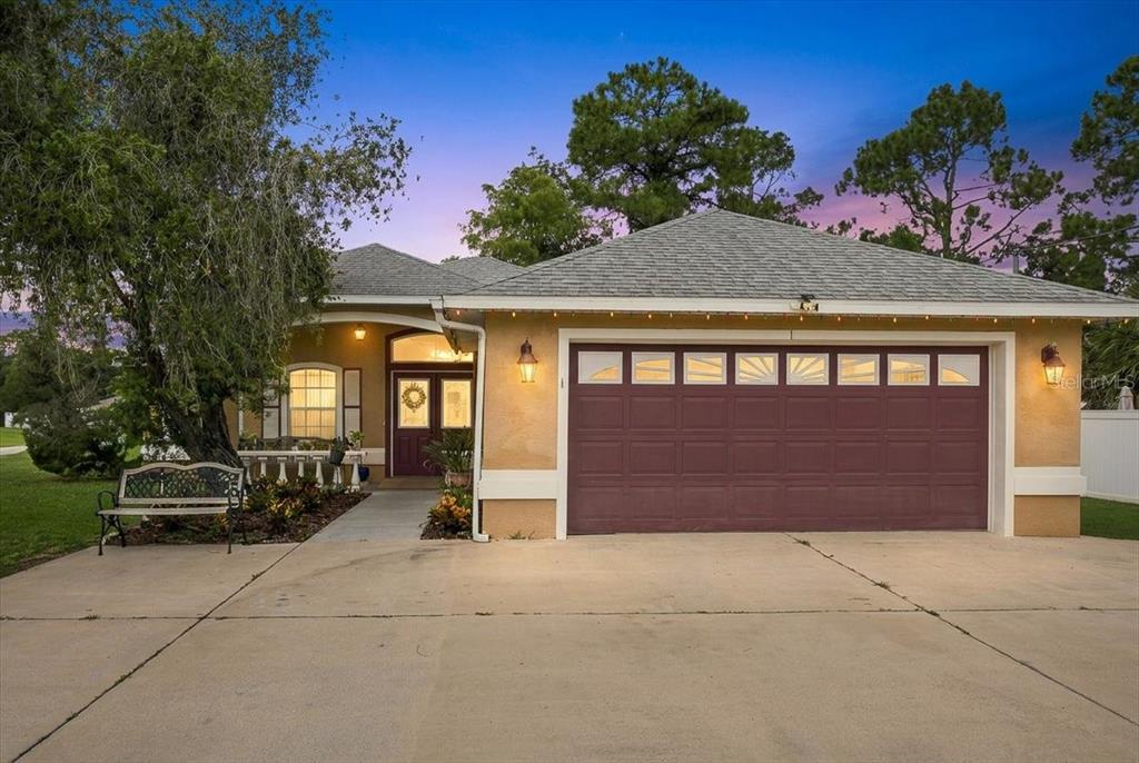 A single-story house with a tan stucco exterior, a two-car garage, and a front bench — 1 PEBBLE WOOD LANE, PALM COAST, FL