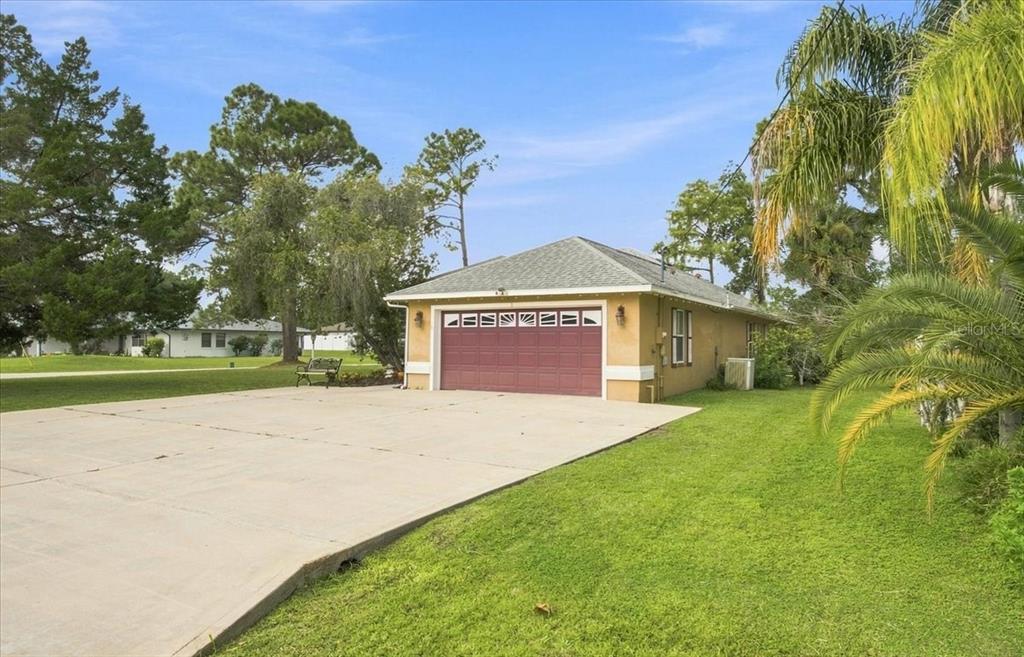 A detached garage with a red door sits on a concrete driveway near a lawn — 1 PEBBLE WOOD LANE, PALM COAST, FL