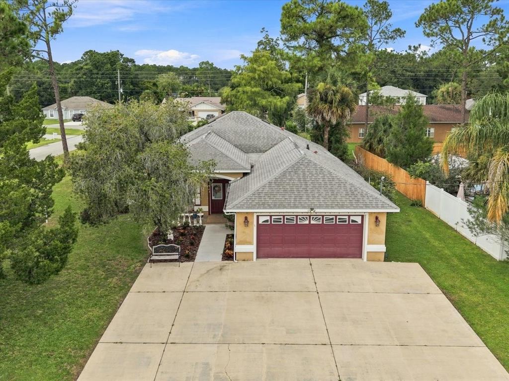 An aerial view of a single-story house with a red garage door and a concrete driveway — 1 PEBBLE WOOD LANE, PALM COAST, FL