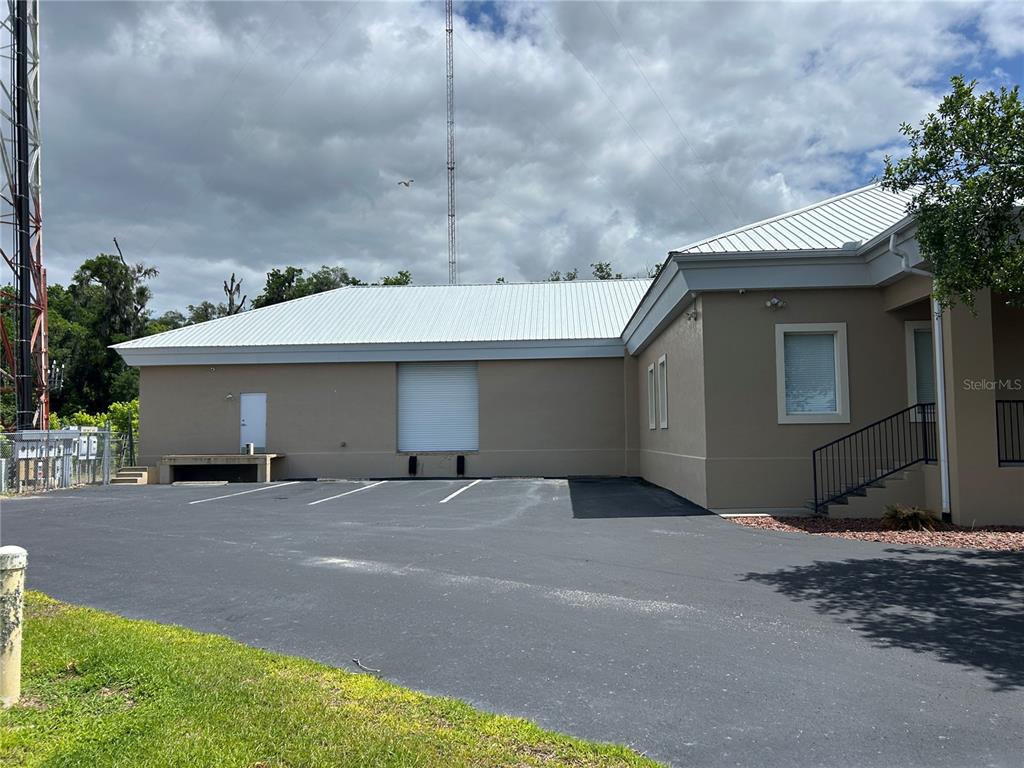 The exterior of a tan commercial building features a metal roof, loading dock, and parking lot — 1137 SW 7TH ROAD, OCALA, FL