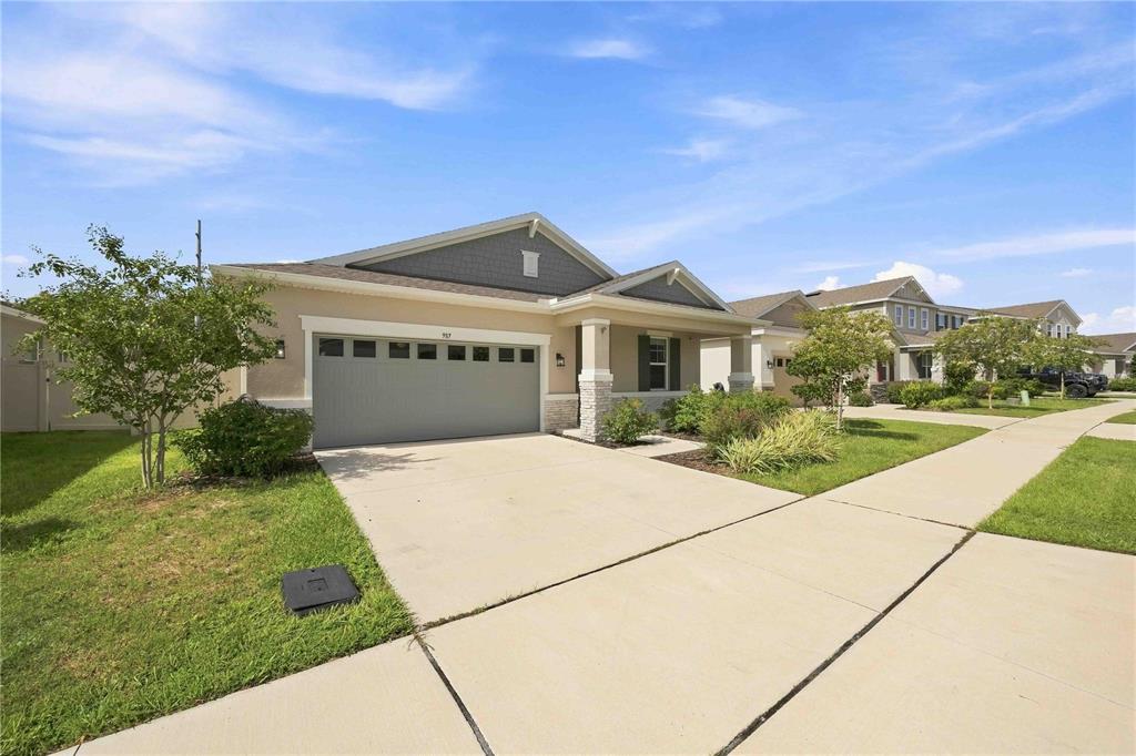 A single-story suburban house with a gray garage door, beige siding, and a covered porch — 987 GRIFFON AVENUE, LAKE ALFRED, FL