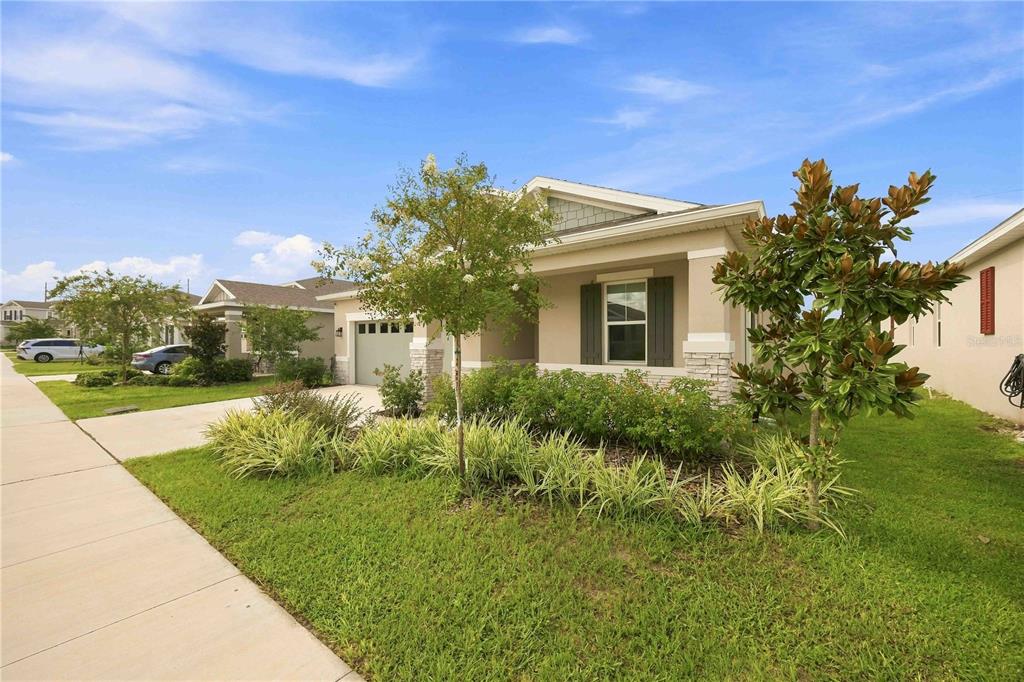 A single-story suburban house with a tan exterior, stone accents, and a landscaped front yard — 987 GRIFFON AVENUE, LAKE ALFRED, FL