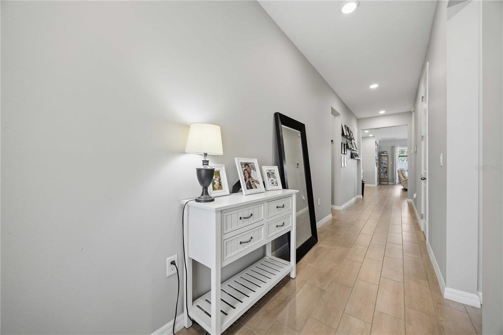 A white console table with a lamp and mirror sits in a hallway with tile flooring — 987 GRIFFON AVENUE, LAKE ALFRED, FL