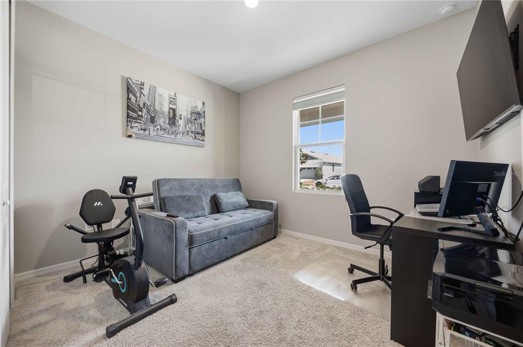 A home office featuring a gray sofa bed, an exercise bike, and a computer desk — 987 GRIFFON AVENUE, LAKE ALFRED, FL