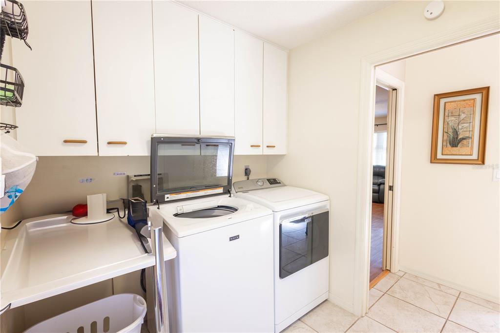 A laundry room features white cabinets, a top-loading washer, a dryer, and tile flooring — 404 N HERON STREET, SEBRING, FL