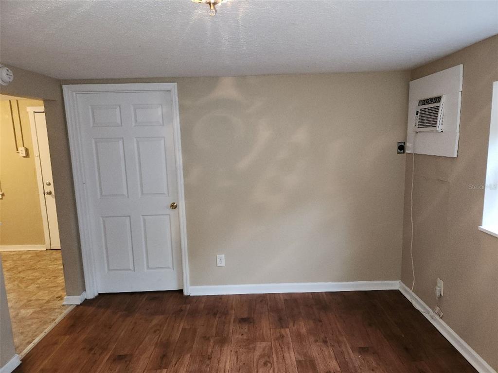 A room with wood-look flooring, a white door, and a wall-mounted air conditioning unit — 2135 8TH AVENUE N UNIT 2, ST PETERSBURG, FL