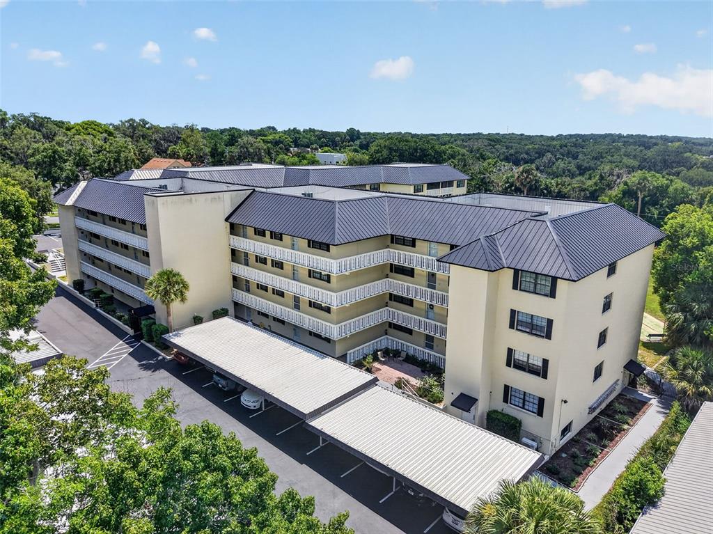 An aerial view of a multi-story apartment building with a metal roof and covered parking — 101 N GRANDVIEW STREET UNIT 412, MOUNT DORA, FL