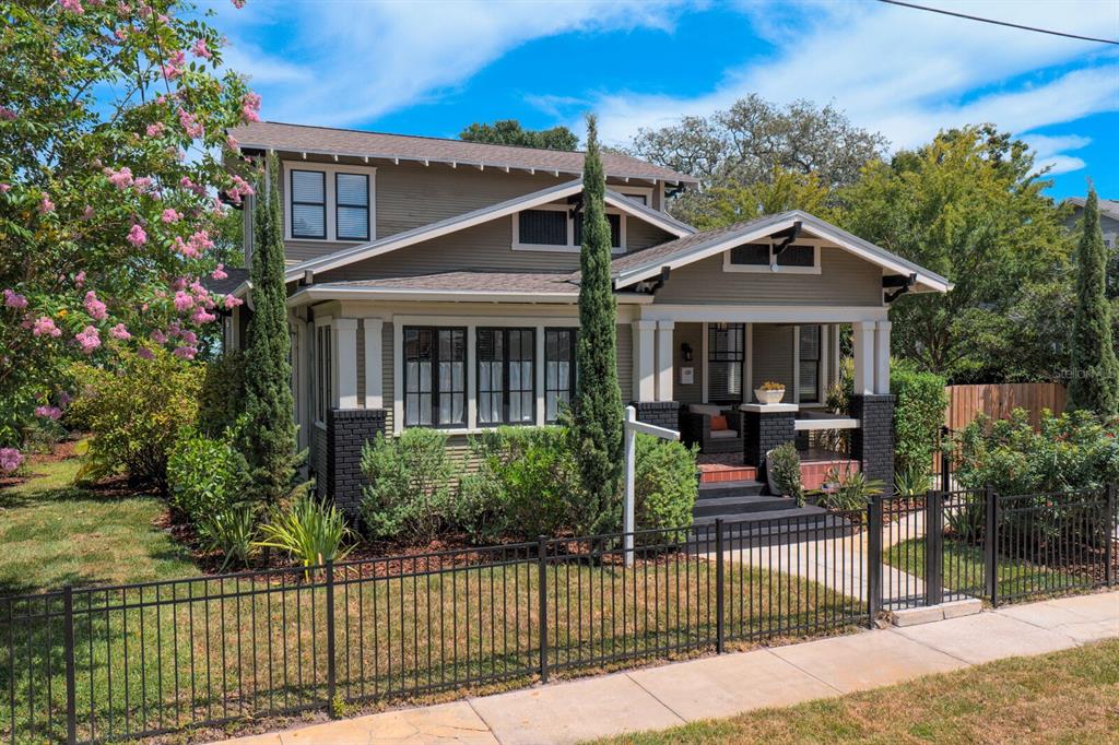 A two-story craftsman-style house with a front porch, dark brick accents, and a metal fence — 705 W WEST STREET, TAMPA, FL