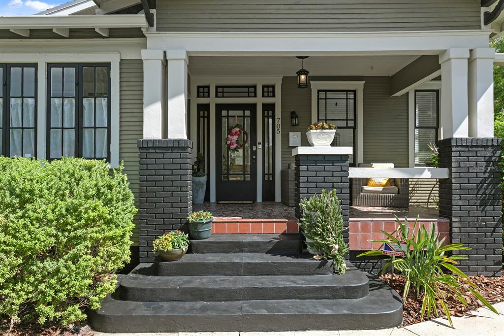 A front porch with black brick columns, concrete steps, and a glass-paneled front door — 705 W WEST STREET, TAMPA, FL
