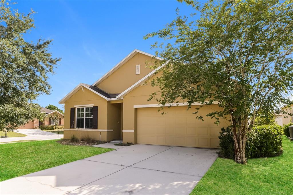A tan single-story house with a two-car garage and a concrete driveway — 2301 SEQUOIA WAY, DAVENPORT, FL