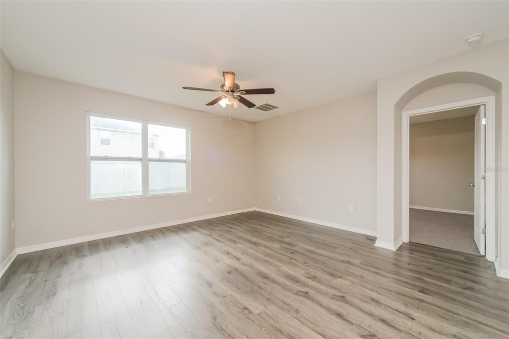 A bedroom with light-colored walls, wood-look flooring, a ceiling fan, and an arched doorway — 2301 SEQUOIA WAY, DAVENPORT, FL