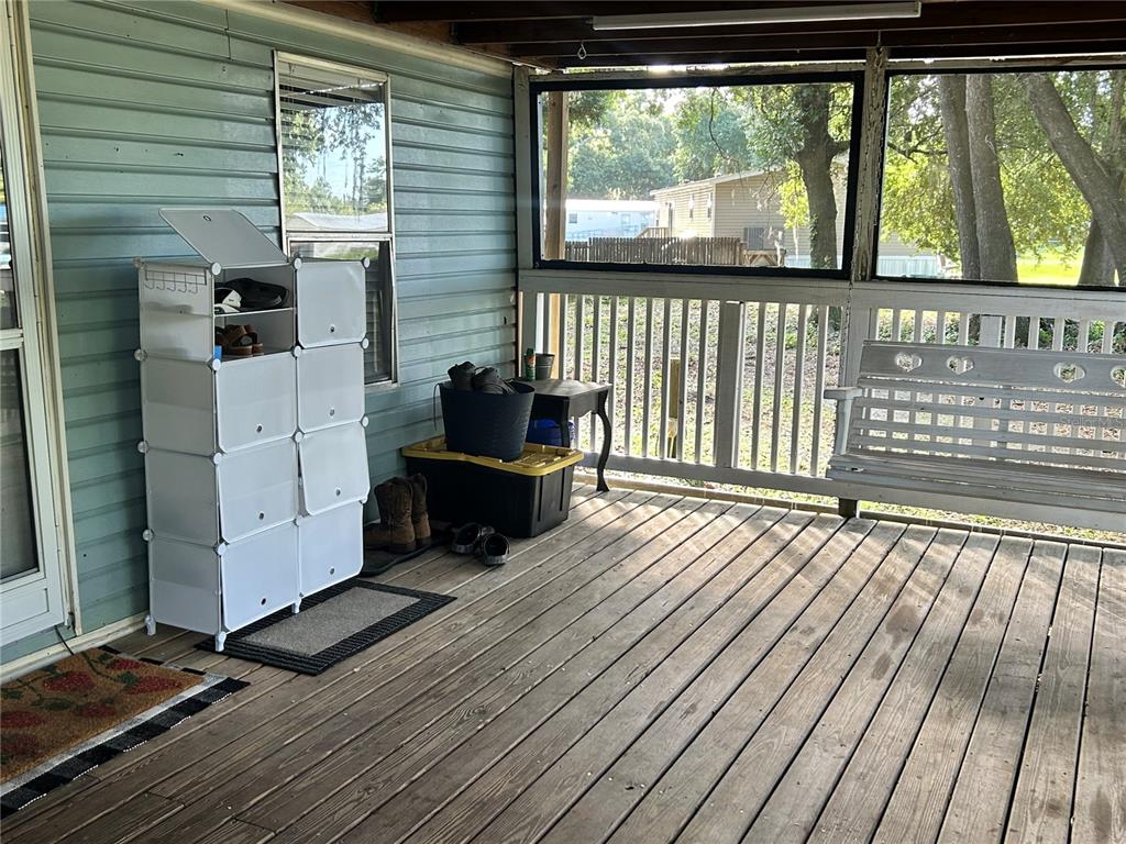 A covered wooden porch features a white modular shoe rack, storage bins, and a hanging bench — 5237 TURTLE DOVE TRAIL, LAKELAND, FL