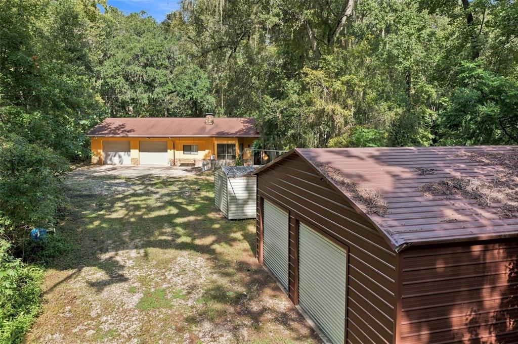 An exterior view of a yellow house with a garage and a separate metal shed — 16205 PERIMETER DRIVE, BROOKSVILLE, FL