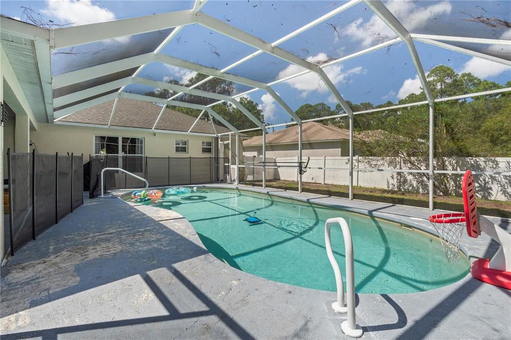 A screened-in swimming pool with a basketball hoop and a safety fence on a patio — 57 RYARBOR DRIVE, PALM COAST, FL