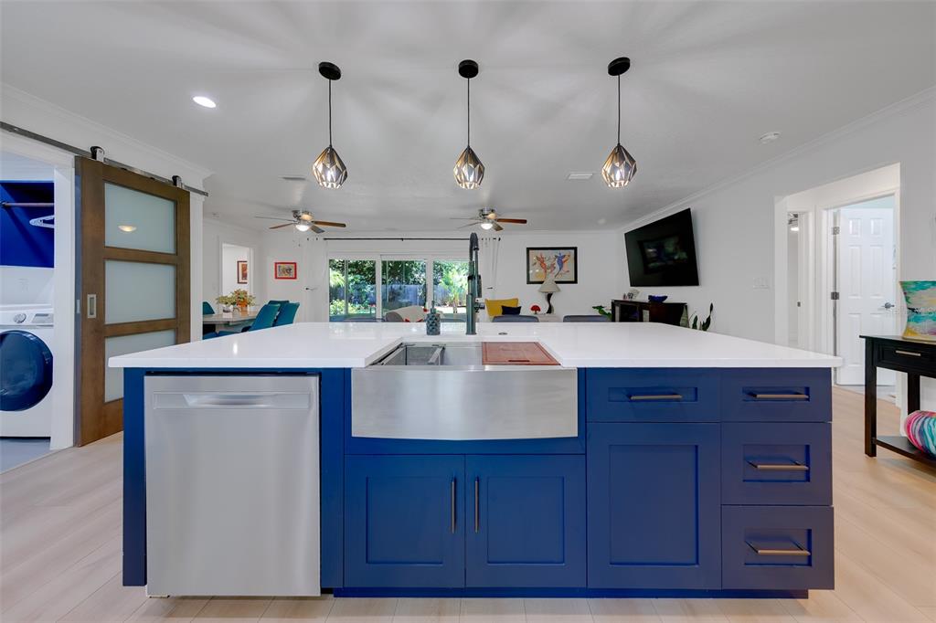 A kitchen island with a stainless steel farmhouse sink and blue cabinetry sits in a room — 2043 DODGE STREET, CLEARWATER, FL