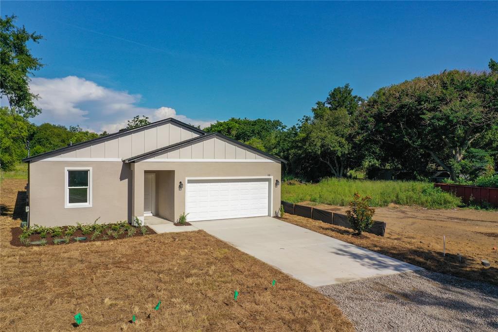 A newly constructed single-story house with a white garage door and beige siding — 110 FRUITWOOD AVENUE, EUSTIS, FL