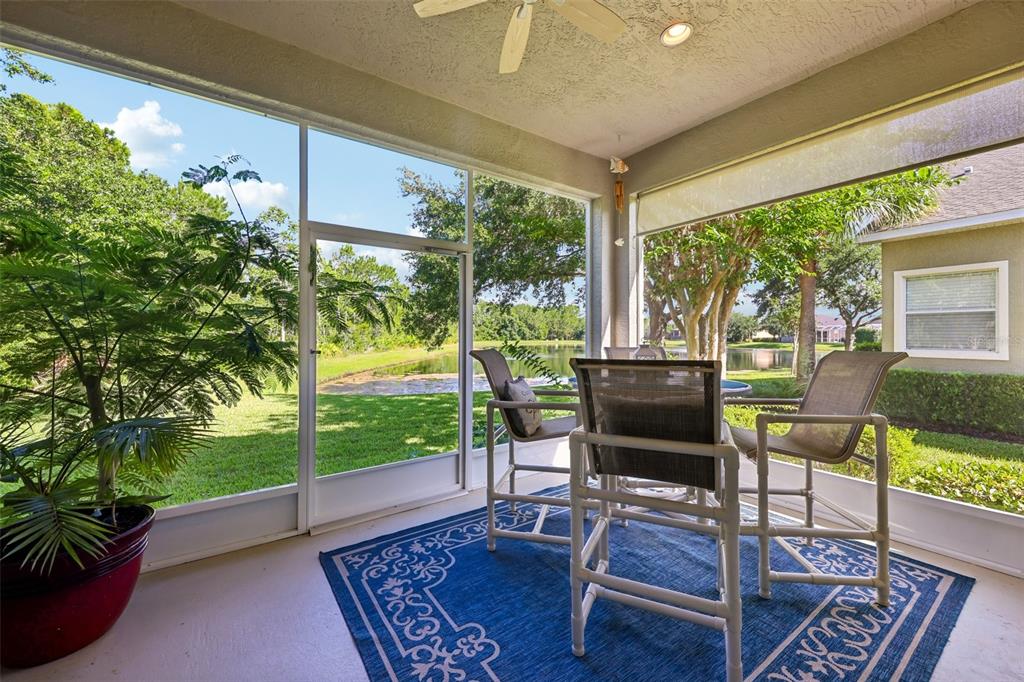 A screened-in patio features a blue patterned rug, patio furniture, and a view of water — 456 CHELSEA PLACE AVENUE, ORMOND BEACH, FL