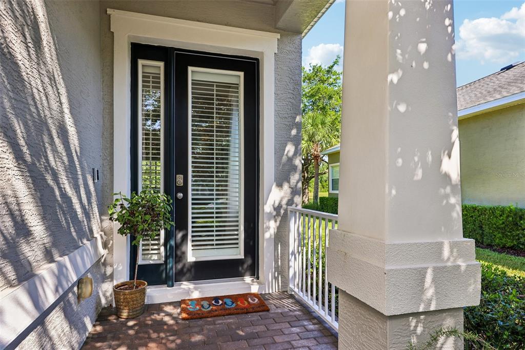 A front porch with a dark-framed glass door, a potted plant, and a welcome mat — 456 CHELSEA PLACE AVENUE, ORMOND BEACH, FL