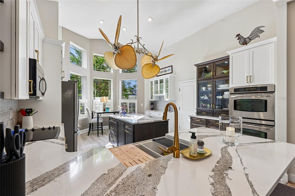 A kitchen features white and dark cabinetry, a large island with a sink, and pendant lighting — 456 CHELSEA PLACE AVENUE, ORMOND BEACH, FL