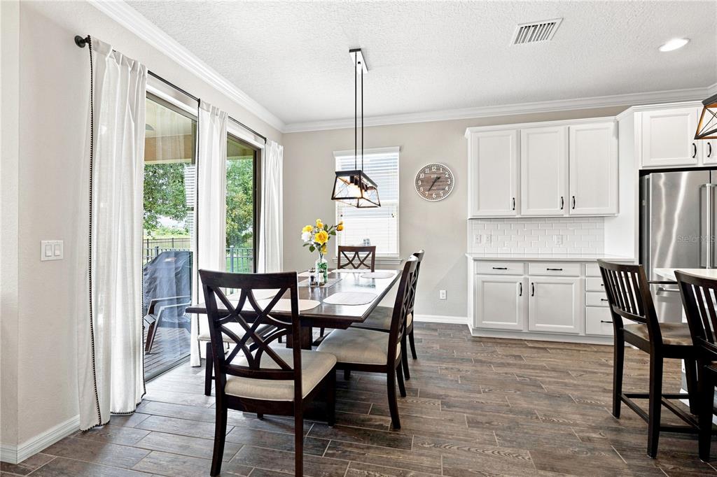 A dining area features a wooden table, white cabinets, and sliding glass doors to a patio — 7278 TWILIGHT BAY DRIVE, WINTER GARDEN, FL