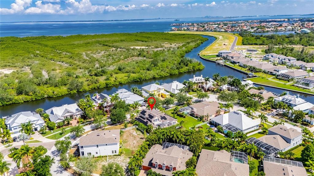 An aerial view shows a residential neighborhood with houses situated along a winding canal — 824 ISLEBAY DRIVE, APOLLO BEACH, FL