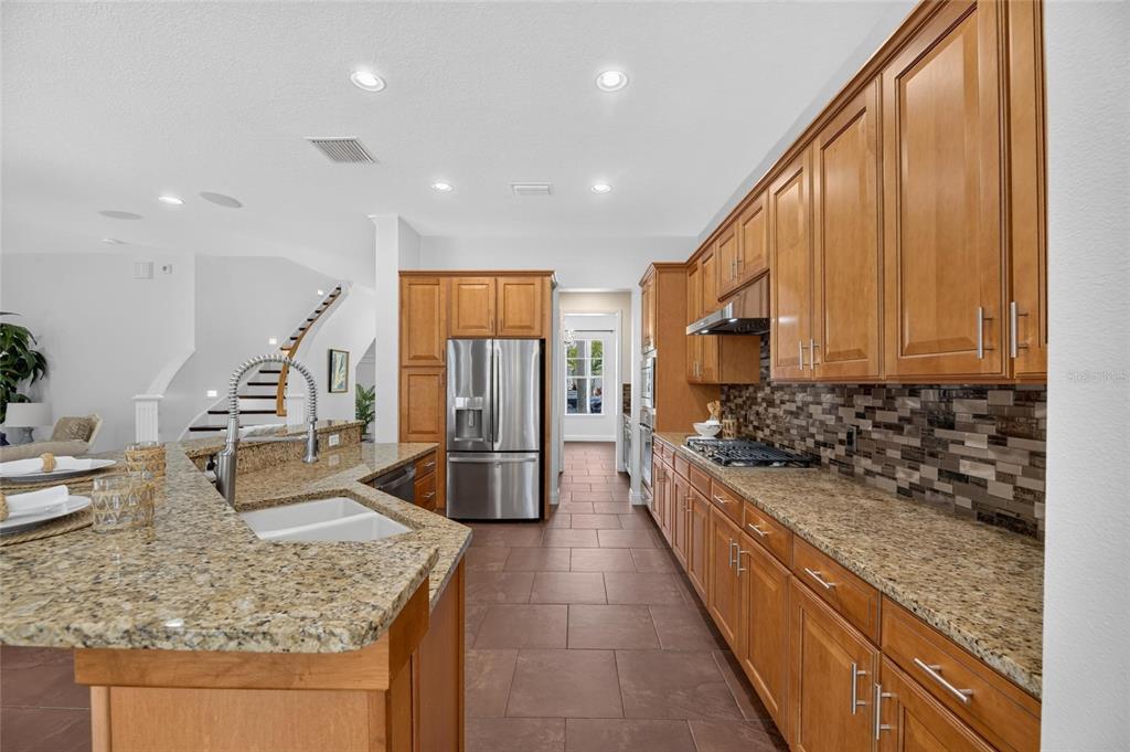 A kitchen features wood cabinets, granite countertops, a tile backsplash, and stainless steel appliances — 824 ISLEBAY DRIVE, APOLLO BEACH, FL