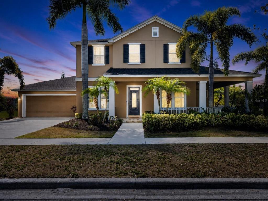 A two-story suburban house with a tan exterior, dark shutters, and a front porch — 824 ISLEBAY DRIVE, APOLLO BEACH, FL